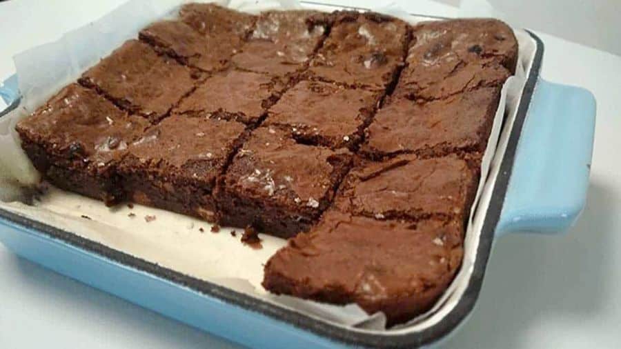 Brownies recém-assados em uma forma retangular azul, cortados em quadrados e prontos para servir