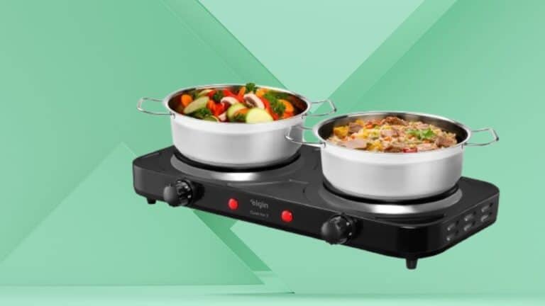 Cooktop elétrico portátil com duas bocas, cozinhando legumes e carne em panelas de aço inox sobre fundo verde