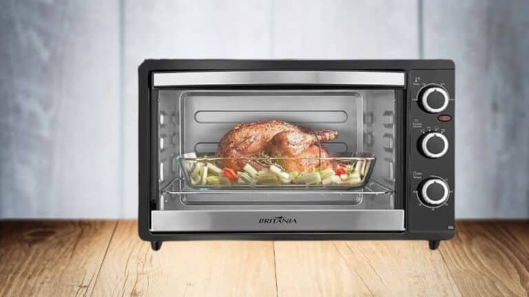 Forno elétrico Britânia com frango assado em travessa de vidro sobre bancada de madeira, usada como imagem destacada do artigo