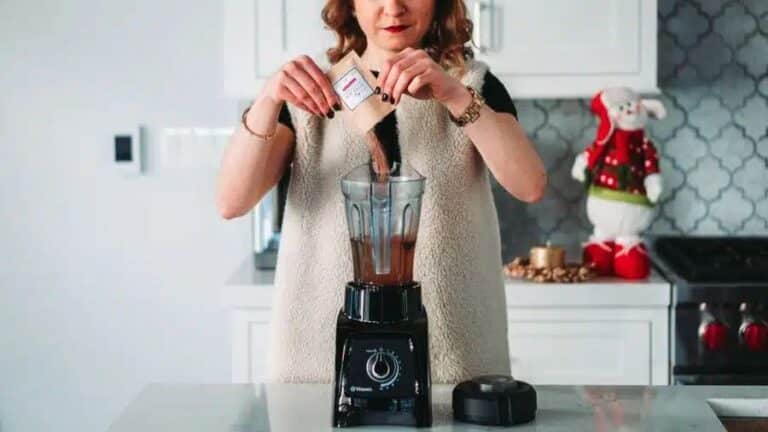 Mulher adicionando ingredientes em um liquidificador potente na cozinha