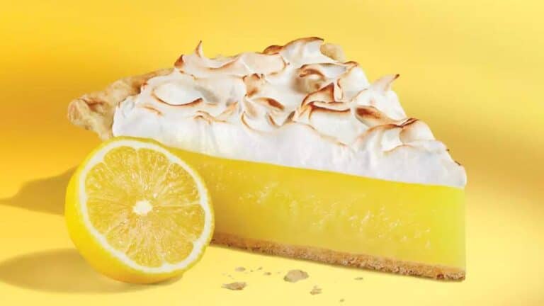 Fatia de torta de limão com cobertura de merengue ao lado de meio limão, usada como imagem destacada do artigo