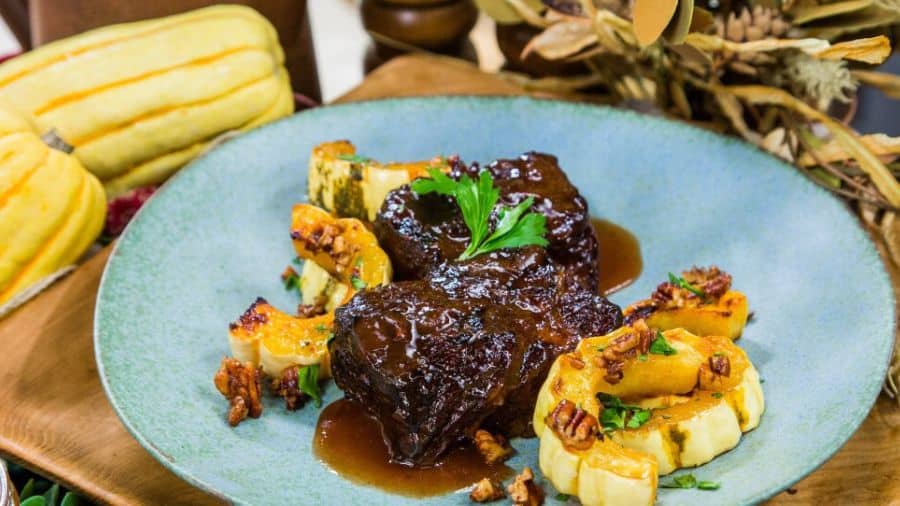 Costela na panela de pressão com molho barbecue, em fatias suculentas acompanhadas de molho extra no prato