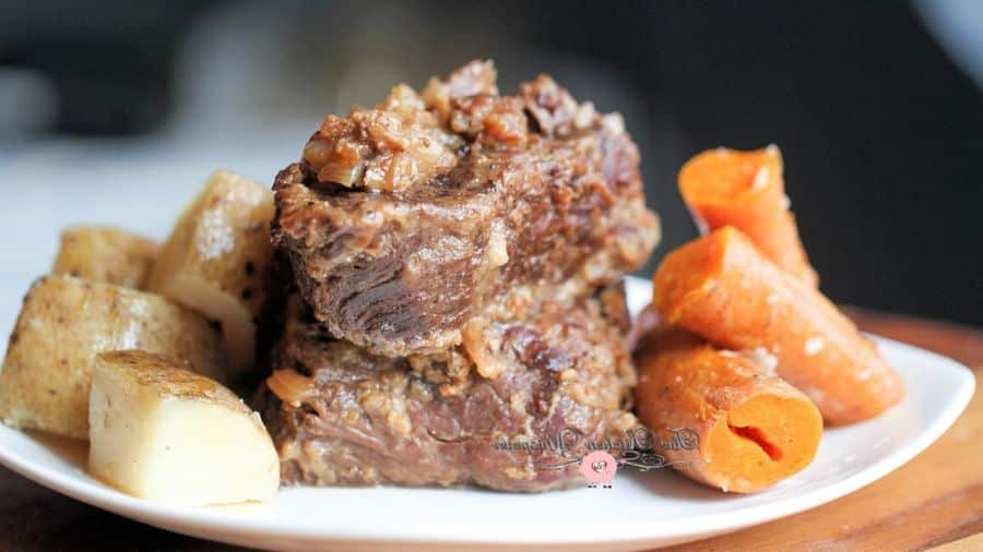 Costela na panela de pressão servida com batatas e cenouras no prato branco