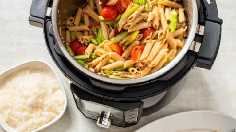 Macarrão penne com legumes e tomate-cereja em panela de pressão elétrica, usada como imagem destacada do artigo