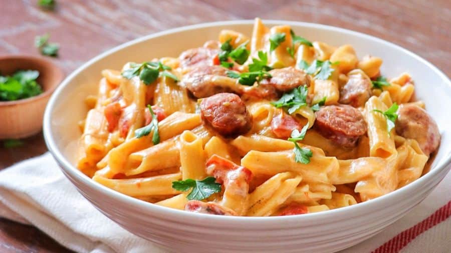 Macarrão cremoso com calabresa em rodelas servido em prato fundo