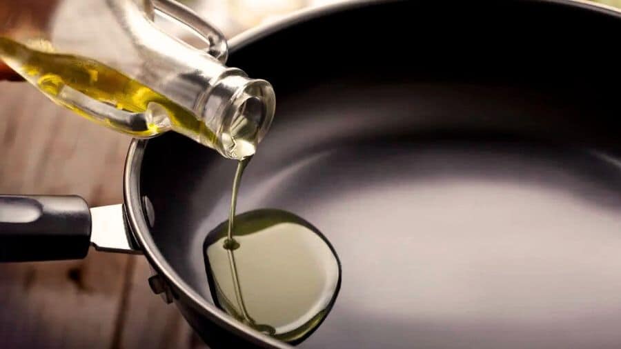 Óleo sendo despejado em frigideira antiaderente nova, usada como imagem destacada do artigo